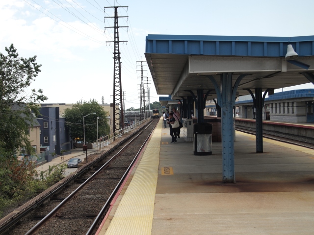 A LIRR train pulls around a slight curve and intro an elevated platform.